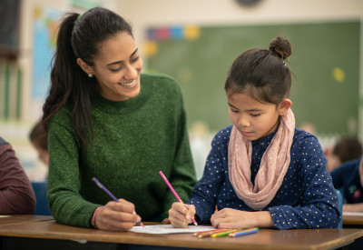 Adult working with child in classroom